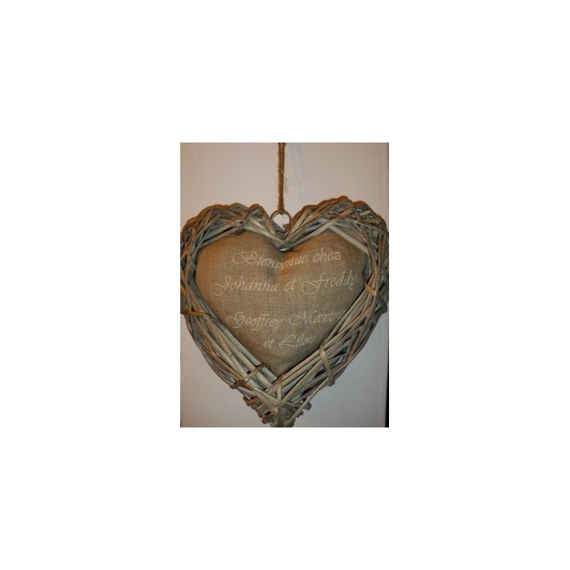 Coeur en rotin contenant un coussin sur lequel sont brodés les prénoms composant le foyer de la maison